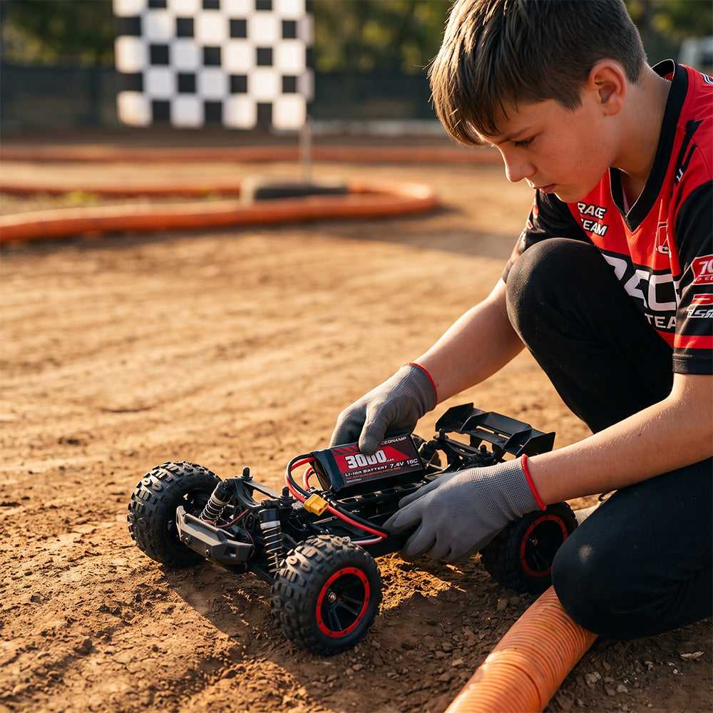 A young RC racer in a red and black “RC TEAM” jersey and work gloves crouches on a dirt track, installing a PCEONAMP 3000mAh 7.4V 2S Li-ion battery into a 4WD RC buggy, with a checkered finish line flag and orange track barriers in the background, golden hour lighting.